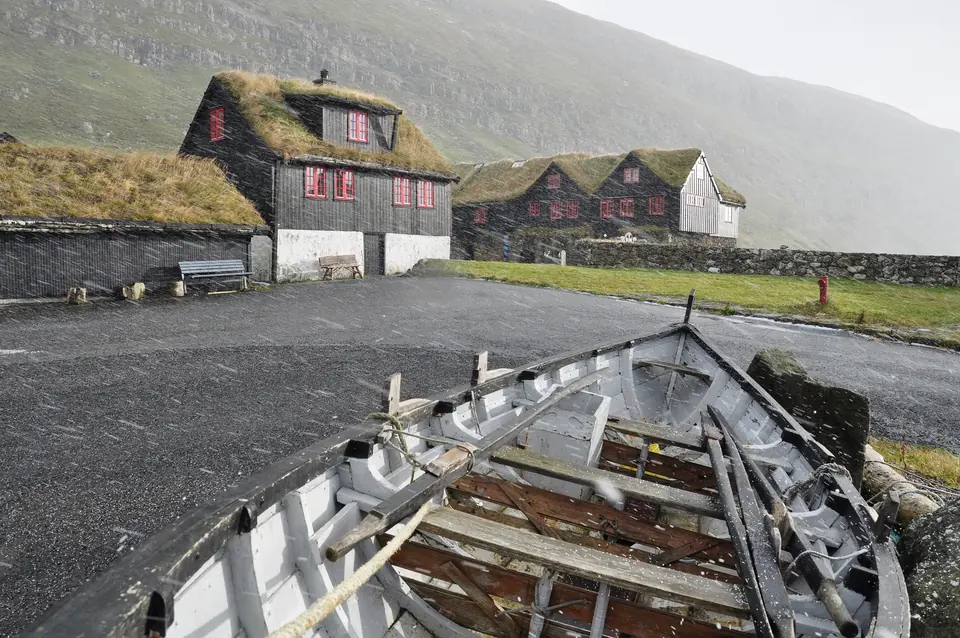 Ein altes Holzboot vor den Häusern von Kirkjubøur