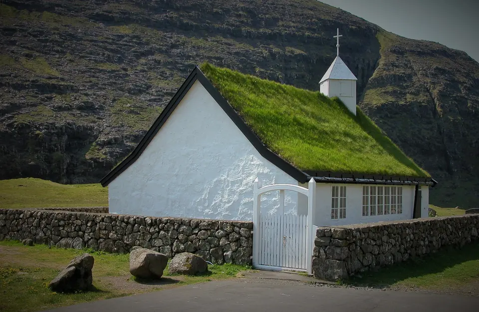 Die weiße Kirche mit Grasdach in Saksun vor den Bergen
