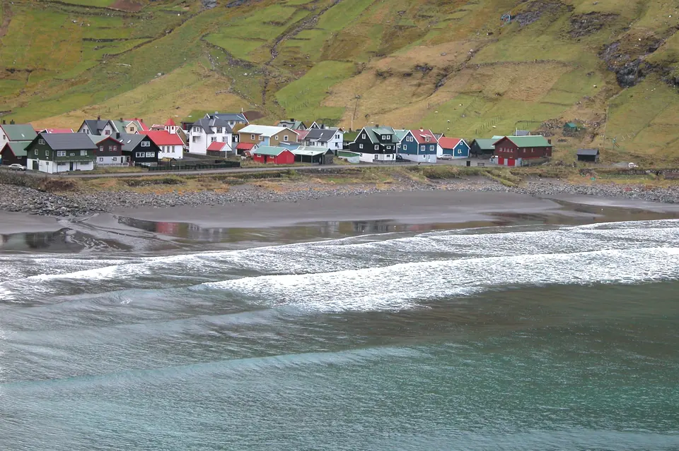 Svart sandstrand och hus i Tjørnuvík